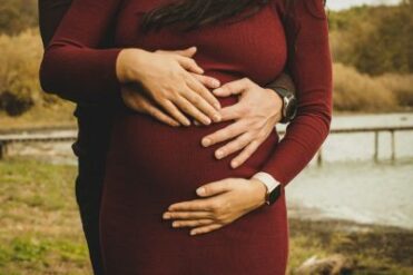 Un ventre de femme enceinte entourée de mains car la réflexologie peut aussi être palmaire et est adaptée aux femmes enceintes en complément de la réflexologie plantaire